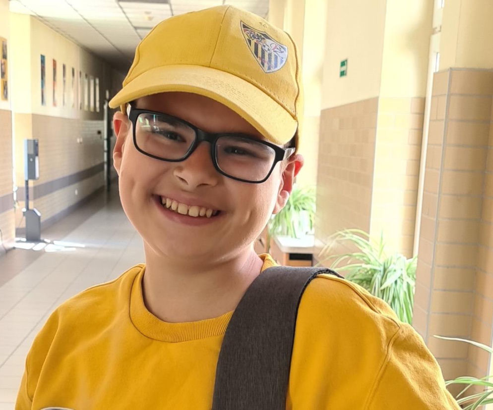 Uśmiechnięty 15-letni Filip w żółtej czapce z daszkiem i okularach. O zbiórce na terapię przeczytasz na Poradnik Zdrowie.