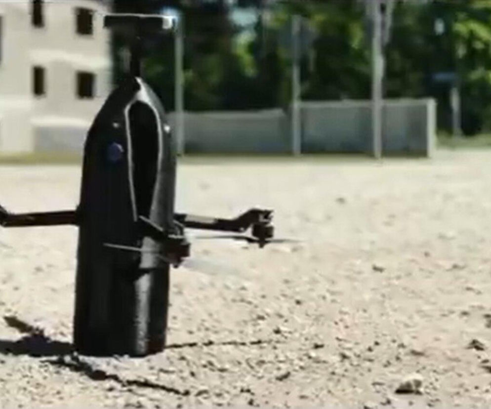 Ciemny dron AVALON o pionowej budowie stoi na piaszczystym podłożu. O testach sprzętu przeczytasz na SE Portal Obronny.