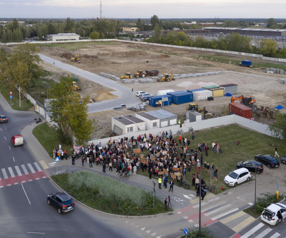 Grupa protestujących osób z transparentami przed placem budowy centrum danych. O kontrowersjach przeczytasz w Architektura.