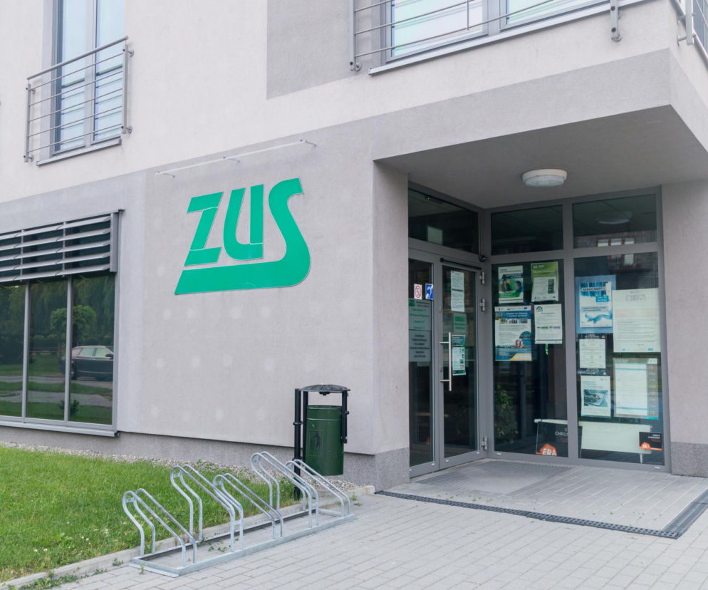 Budynek ZUS z zielonym logo na fasadzie, wejściem z plakatami informacyjnymi oraz stojakiem na rowery. Poradnik Zdrowie informuje o zmianach w L4, nowych prawach ZUS i pracowników od 2026 roku.