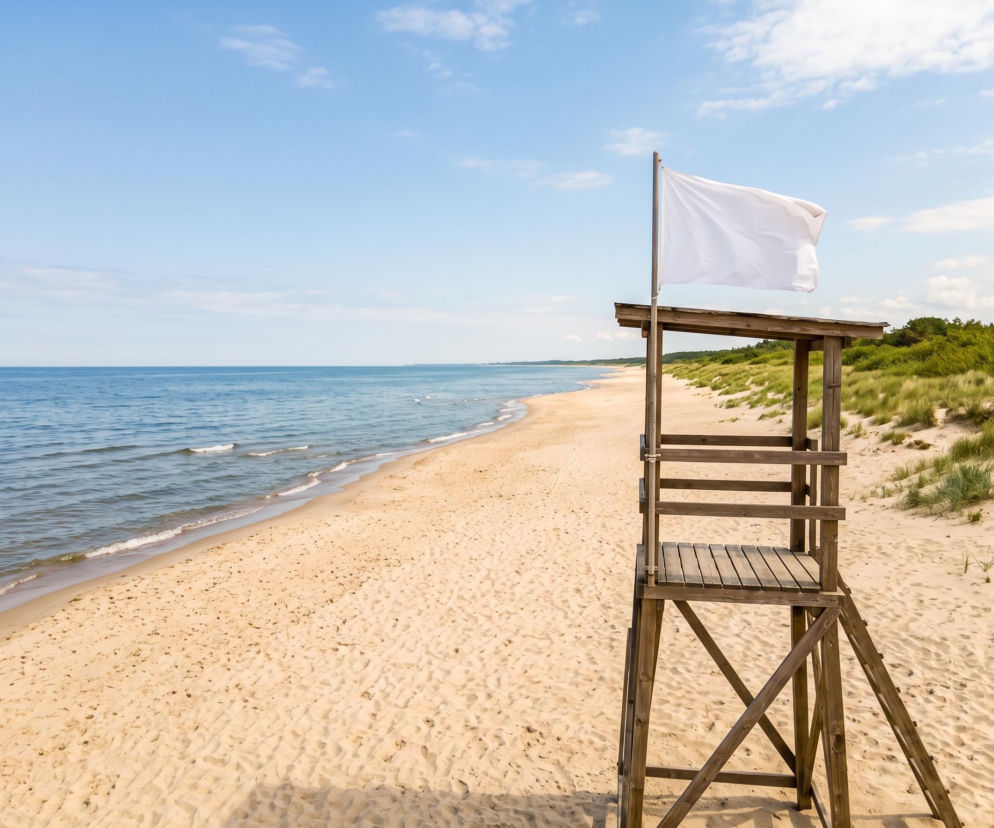 Drewniana wieża ratownika z białą flagą na pustej plaży w Grzybowie. O pogodzie nad morzem przeczytasz na SE Szczecin.