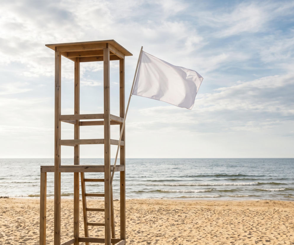 Drewniana wieża ratownicza z białą flagą na plaży w Mielnie. O bezpieczeństwie kąpieli przeczytasz na SE Szczecin.