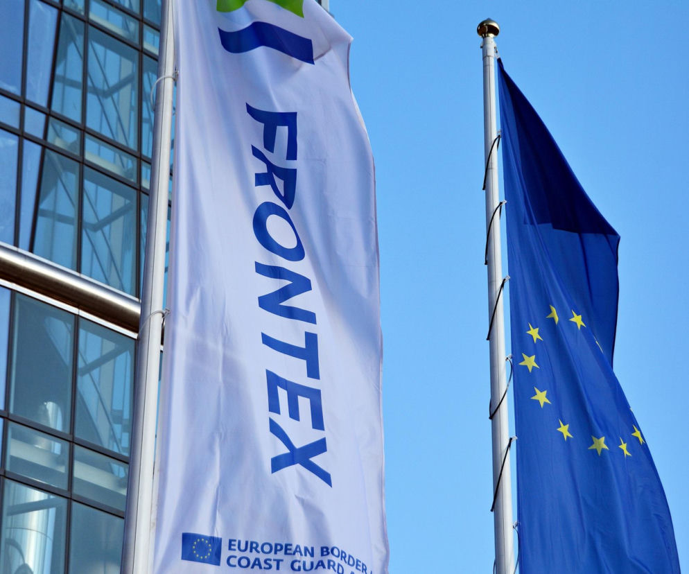 Flagi Frontexu i Unii Europejskiej przed przeszklonym biurowcem. O budowie nowej siedziby na Mokotowie przeczytasz na Muratorplus.