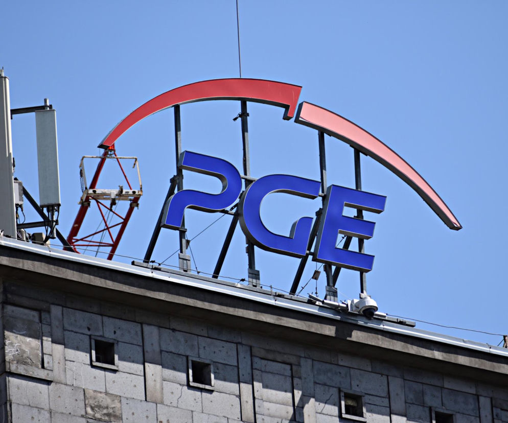 Niebieskie, świecące litery logo PGE na dachu budynku. Nad literami czerwony, łukowaty element. Z lewej strony widoczne anteny telekomunikacyjne. Kontekst zmian w radzie nadzorczej PGE. Więcej o Super Biznes.