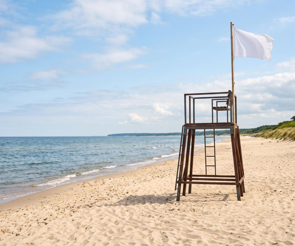 Wieża ratownicza z białą flagą na piaszczystej plaży w Świnoujściu. O warunkach nad wodą przeczytasz na SE Szczecin.
