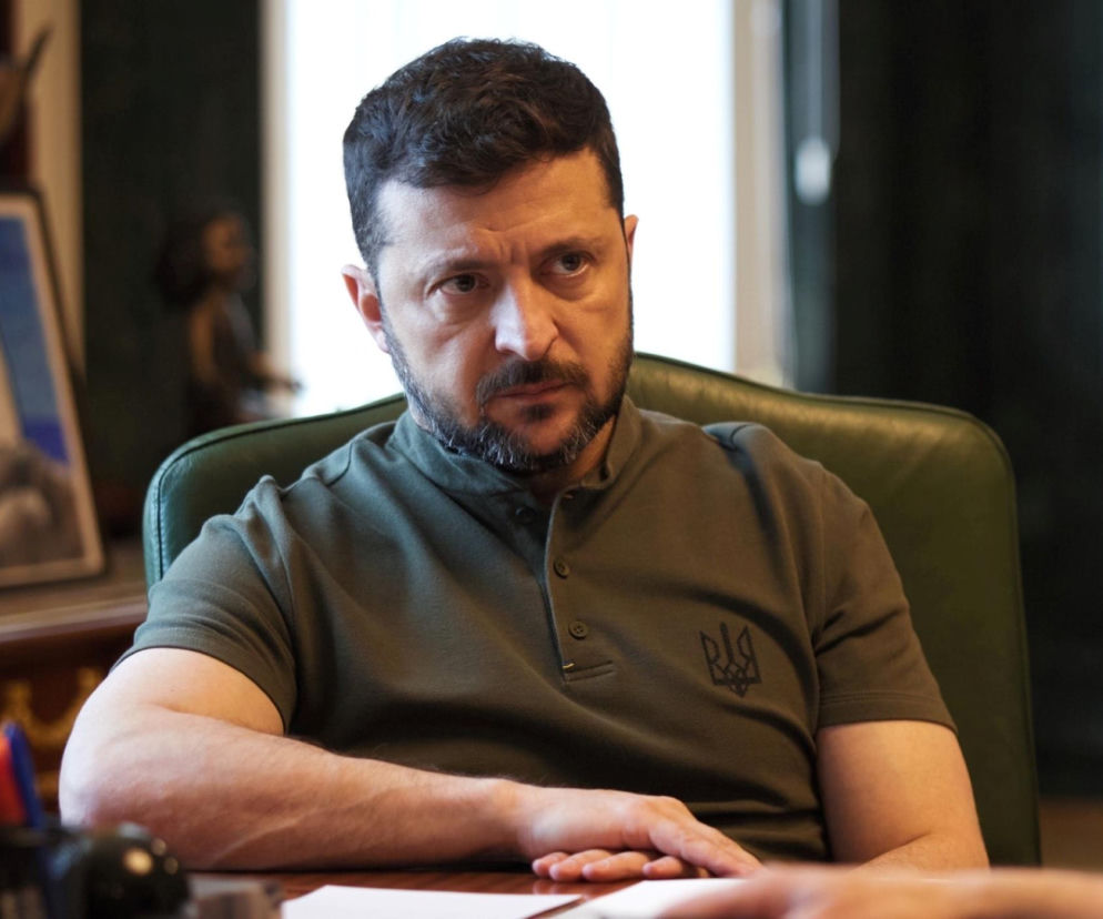 Prezydent Wołodymyr Zełenski w oliwkowej koszulce siedzi przy biurku. O Panteonie Narodowym przeczytasz na SE Polityka.