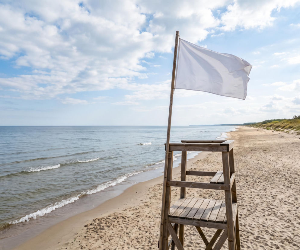 Biała flaga na wieży ratowniczej przy pustej plaży w Grzybowie. O pogodzie nad Bałtykiem dowiesz się z SE Szczecin.