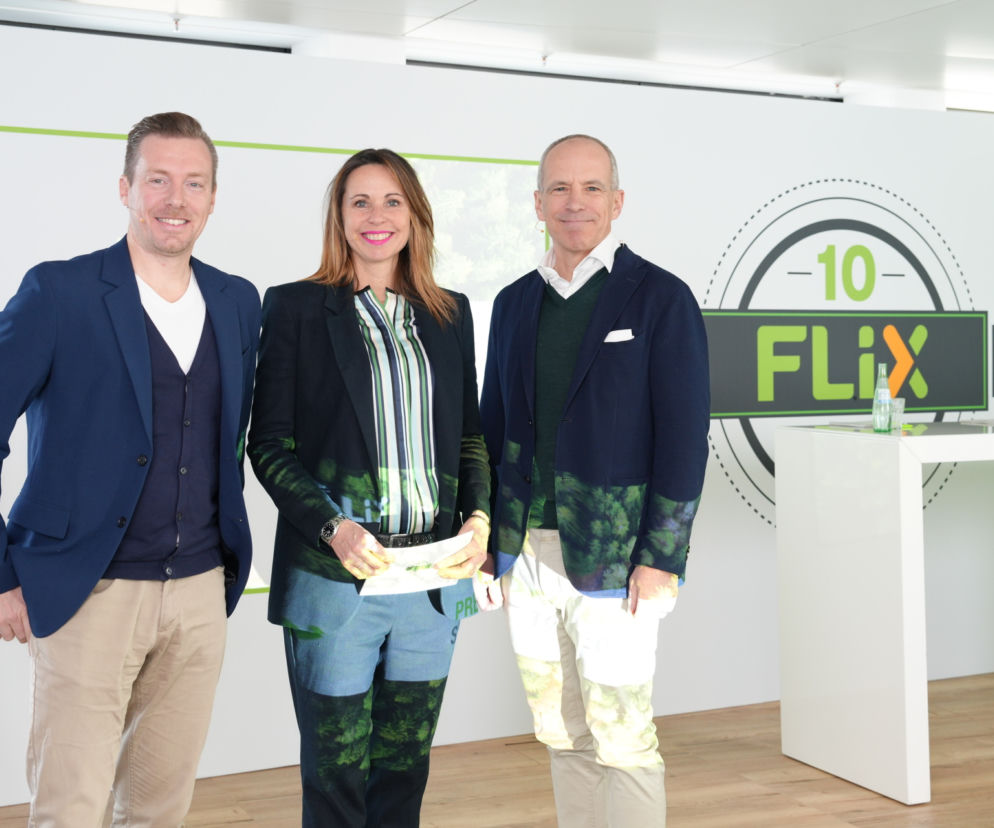 Trzy osoby pozujące na tle ścianki z logo -10- FLIX, świętując rekordowe wyniki FlixBusa w 2022 roku. Temat dostępny na Super Biznes.