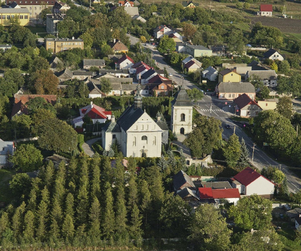 Widok z lotu ptaka na miejscowość z kościołem i domami. O najbogatszych wsiach w regionie przeczytasz na Eska Starachowice.
