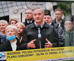 Robert Biedroń na tle religijnego hasła