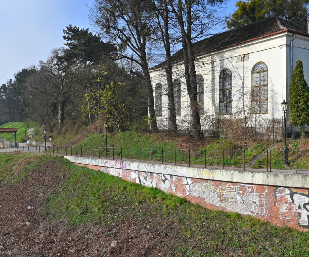 Zbór pomennonicki na Biskupiej Górce w Gdańsku, z białą elewacją i zaokrąglonymi oknami, otoczony drzewami. Budynek, który czeka gruntowny remont, odzyska swoją historyczną formę. Więcej o renowacji zabytków na Architektura Murator Plus.
