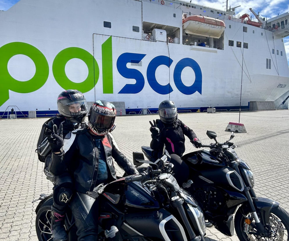 Trójka motocyklistów na czarnych motorach przed białym promem Polsca. O wyprawie do Skandynawii przeczytasz na Eska Szczecin.