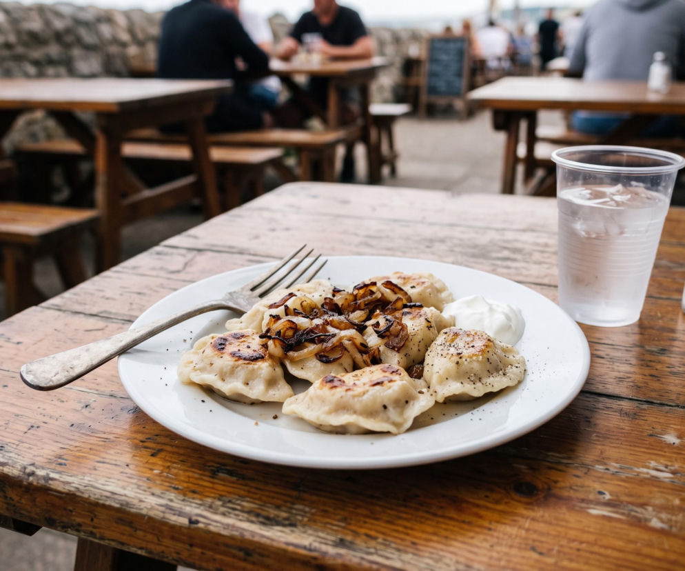 Talerz podsmażanych pierogów z cebulką w letnim ogródku. O tym, jak rozpoznać mrożonkę, przeczytasz na Beszamel.
