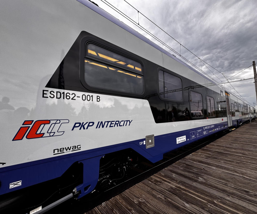 Biało-niebieski pociąg PKP Intercity stoi przy drewnianym peronie. O zniżkach na bilety przeczytasz na SE Superbiz.