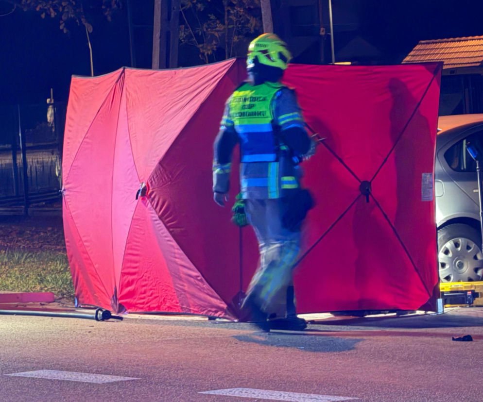 Strażak przechodzi obok rozstawionego czerwonego parawanu na miejscu wypadku. O tragedii w Rybniku przeczytasz na SE.