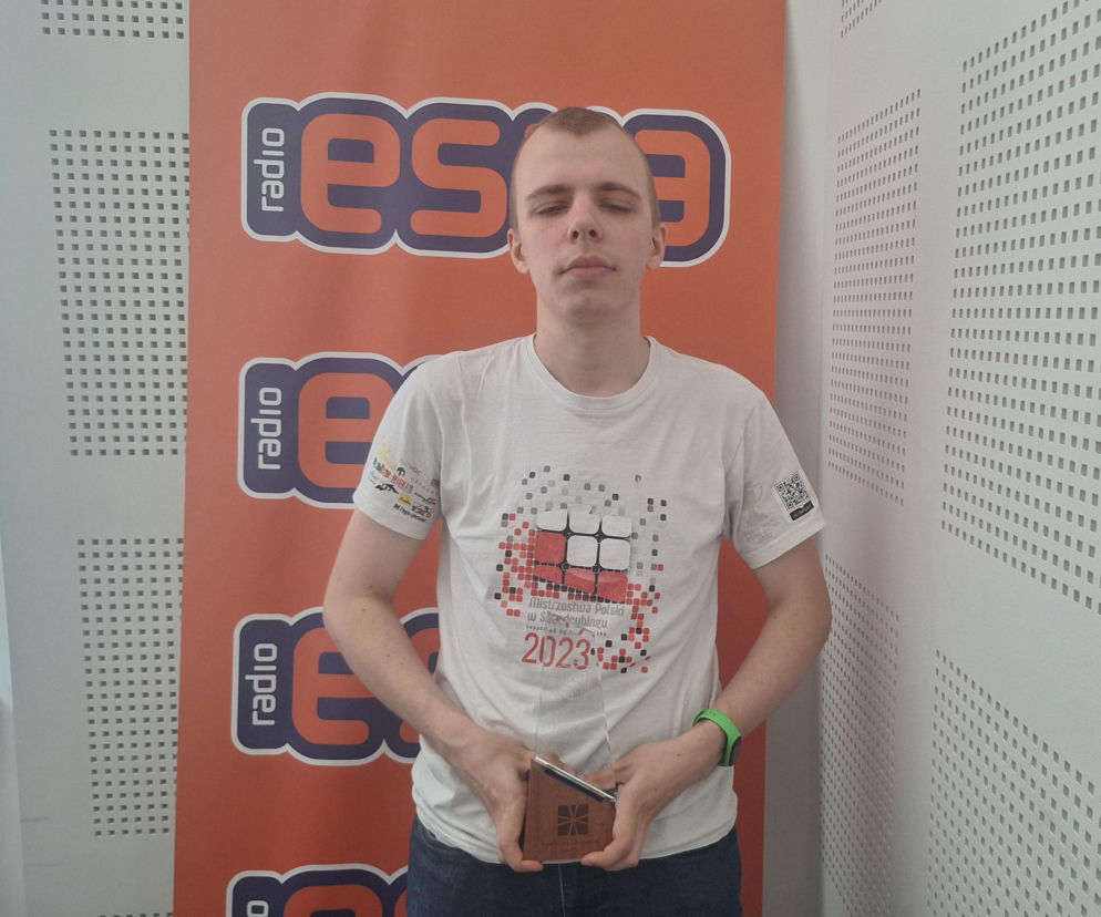 Michał Krasowski ze statuetką na tle logotypu Eska Radom. O jego rekordzie w speedcubingu przeczytasz na Eska Radom.