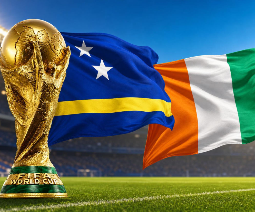 Złoty puchar FIFA World Cup stoi na zielonej trawie stadionu, z powiewającymi flagami Curaçao i Wybrzeża Kości Słoniowej w tle, symbolizując rywalizację w Mundialu 2026, o której przeczytasz więcej na naszym portalu.