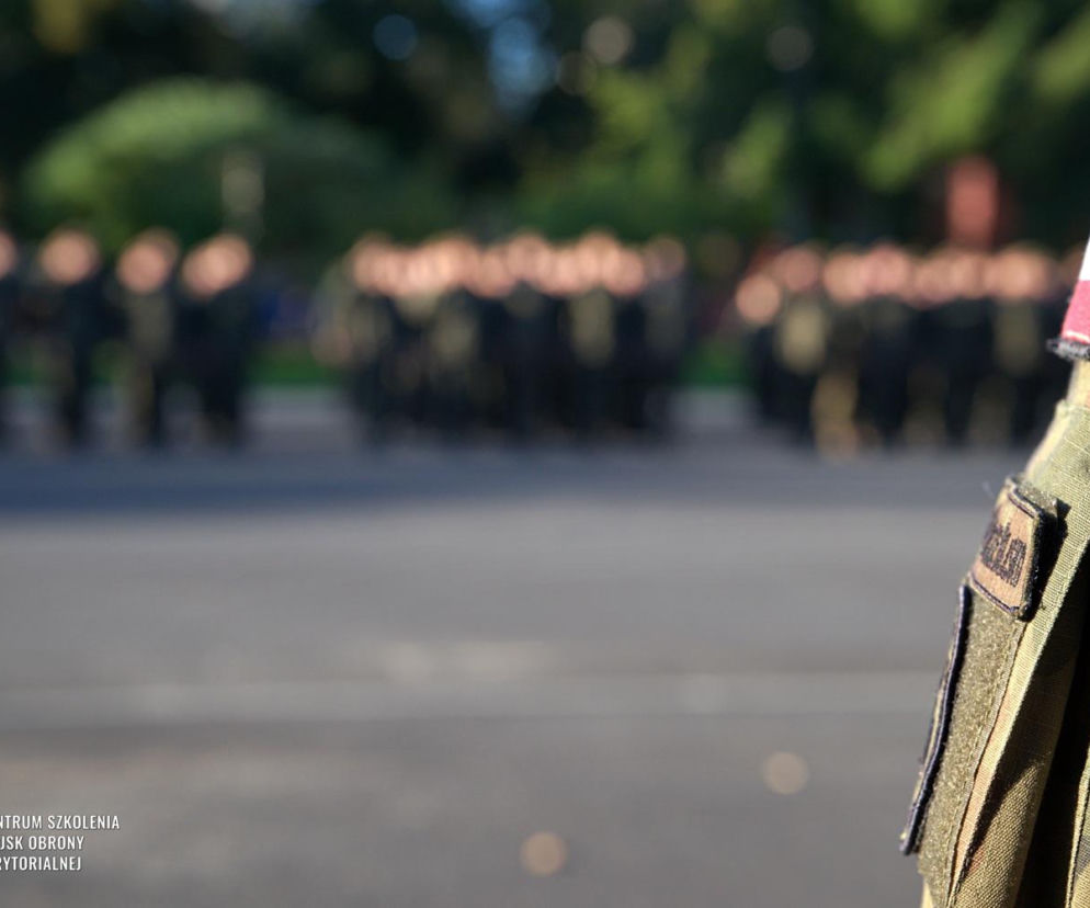 Ramię żołnierza z polską flagą. W tle apel z okazji Święta WOT, o którym przeczytasz na SE Portal Obronny.
