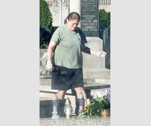 Krystyna Pawłowicz sprząta na grobie rodzinnym