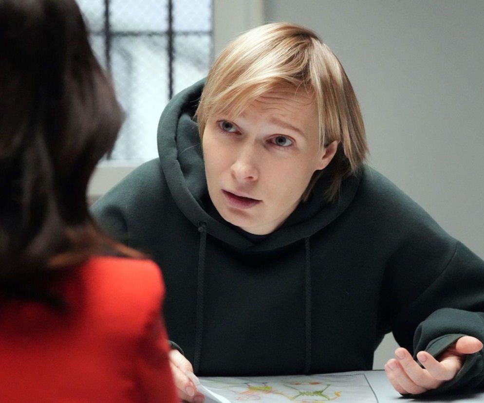 Sonia (Weronika Nockowska) w ciemnej bluzie z kapturem, z jasnymi włosami, rozmawia z Natalią (Maria Dejmek) odwróconą tyłem. Sonia gestykuluje, wyrażając panikę i obawę o zbliżający się proces, czytając o tym na portalu Super Seriale.