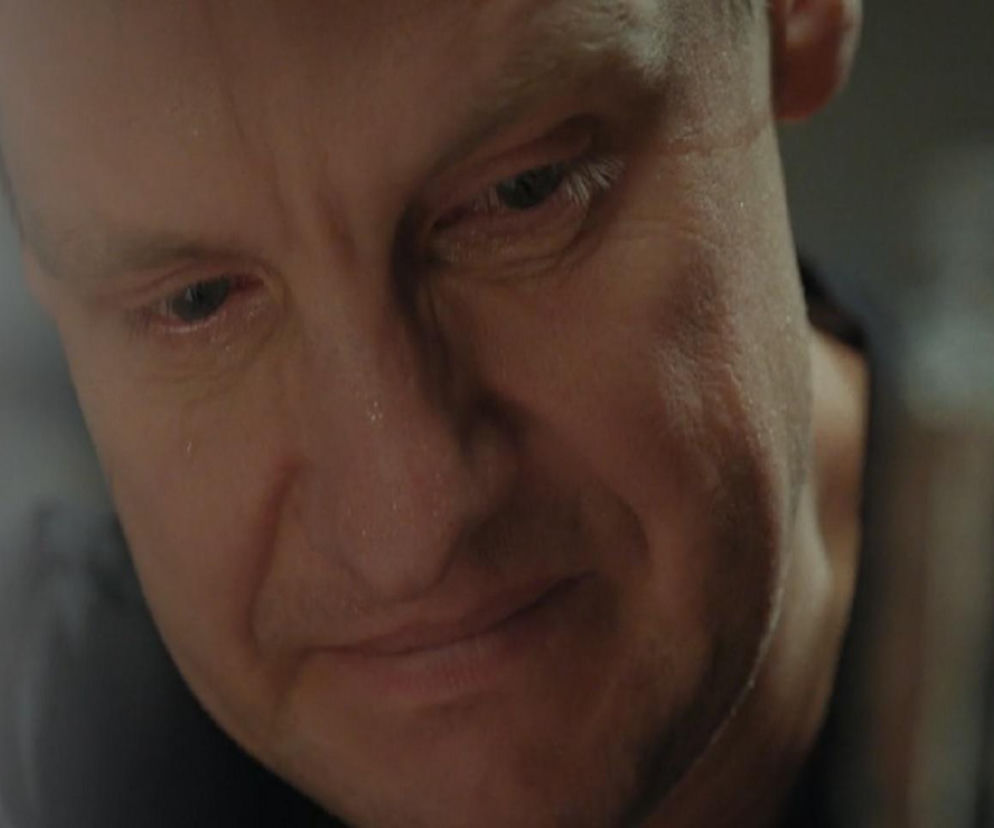 Zasmucona twarz Pawła Zduńskiego z M jak miłość (Rafał Mroczek), z widocznymi zmarszczkami i drobnymi kroplami potu, zamyślonego i zapatrzonego w dół, na tle nieostrego otoczenia. Więcej o losach Pawła na Super Seriale.