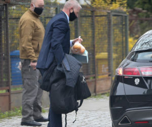 Pięciu ochroniarzy prowadzi Kaczyńskiego do bramy