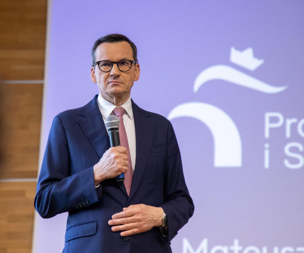 Mateusz Morawiecki trzyma mikrofon na tle logo Prawa i Sprawiedliwości. O sondażu w sprawie nowej partii czytaj w SE Polityka.