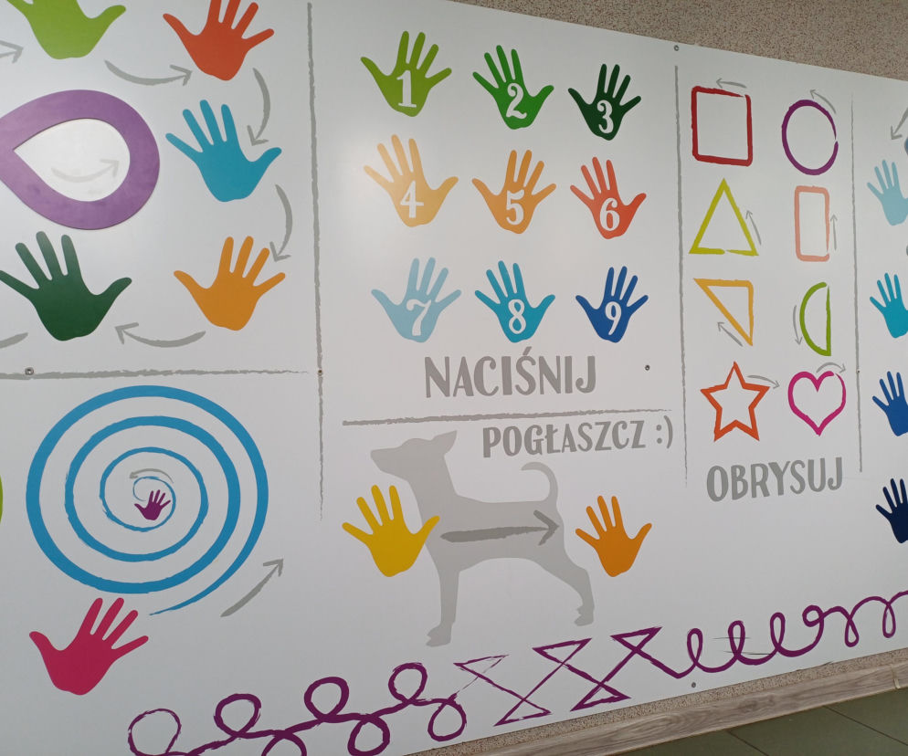 Ściana sensoryczna ze wzorami kolorowych dłoni, kształtów geometrycznych i psa, symbolizująca wsparcie i terapię w Specjalnym Ośrodku Szkolno-Wychowawczym w Ostrzeszowie. Więcej informacji o zbiórce na remont łazienek znajdziesz na naszym portalu.