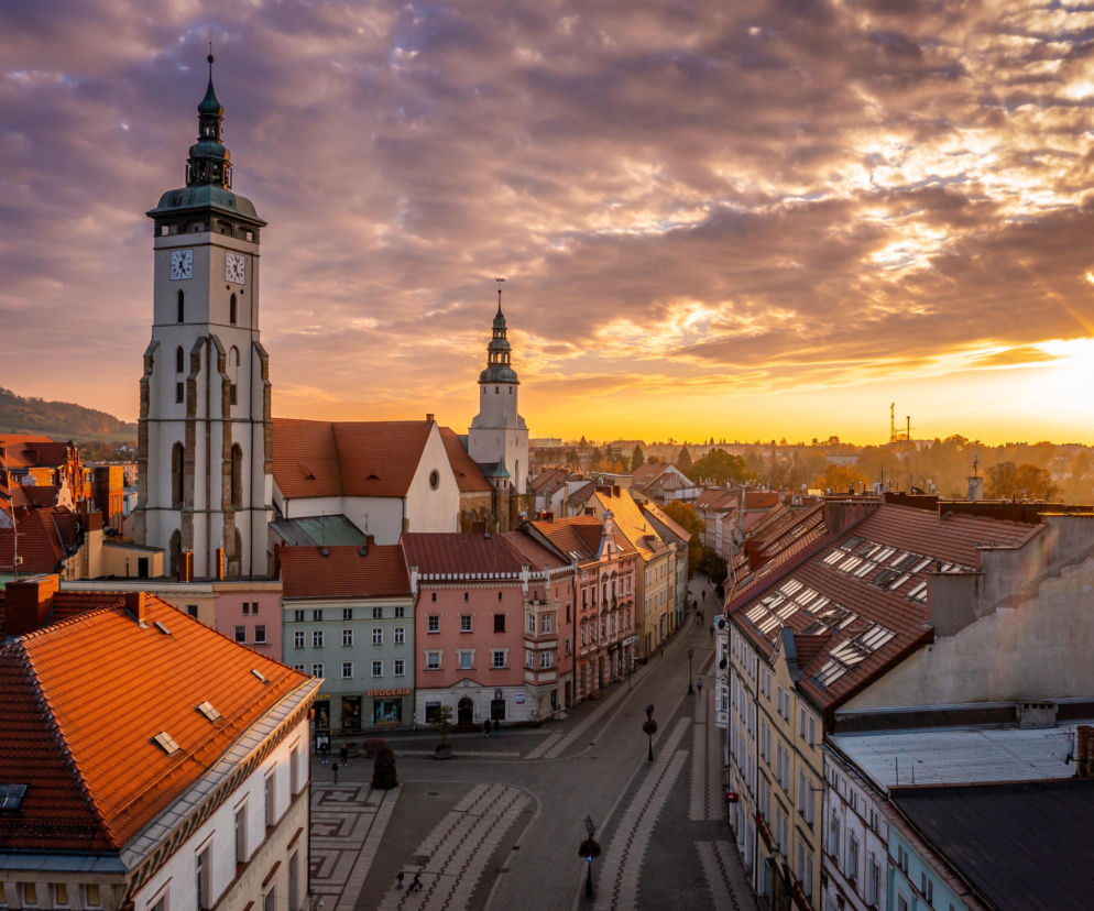 Panorama Złotoryi o zachodzie słońca z widokiem na wieże kościoła i kamienice. O mistrzostwach przeczytasz w serwisie Eska.