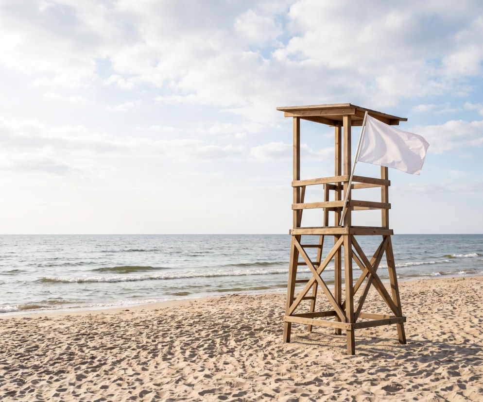 Drewniana wieża ratownicza z białą flagą na plaży w Świnoujściu. O bezpiecznej kąpieli przeczytasz na SE Szczecin.