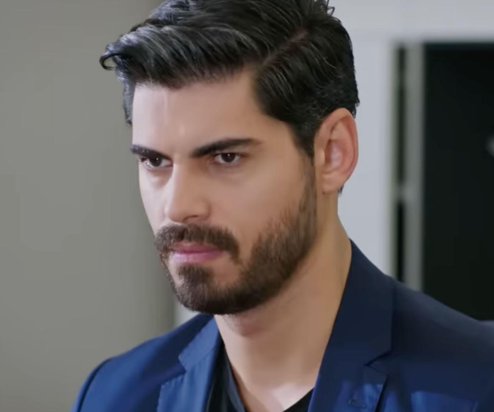 Mężczyzna o ciemnych włosach i brodzie, aktor Türkseve grający Cihana, w ciemnym garniturze, z zamyślonym, lekko zmartwionym wyrazem twarzy. Kontekst dotyczy 82. odcinka serialu Panna młoda, gdzie Cihan dowiaduje się o ciąży Beyzy. Więcej o losach bohaterów na Super Seriale.