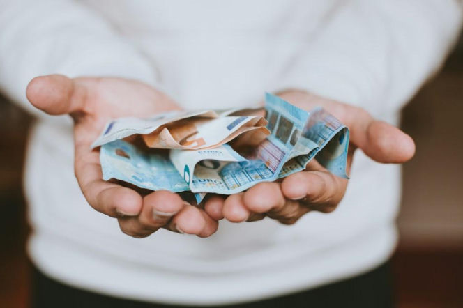 Dłonie osoby trzymającej plik banknotów euro. O limitach i podatku od darowizn w 2026 roku przeczytasz na Eska.