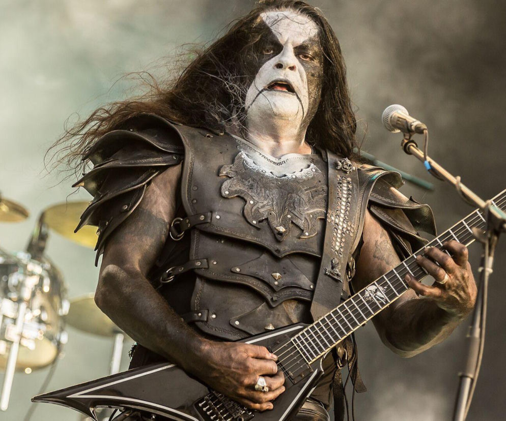 Muzyk Abbath w pełnym makijażu gra na gitarze podczas koncertu. O przerwanym występie artysty przeczytasz na EskaRock.
