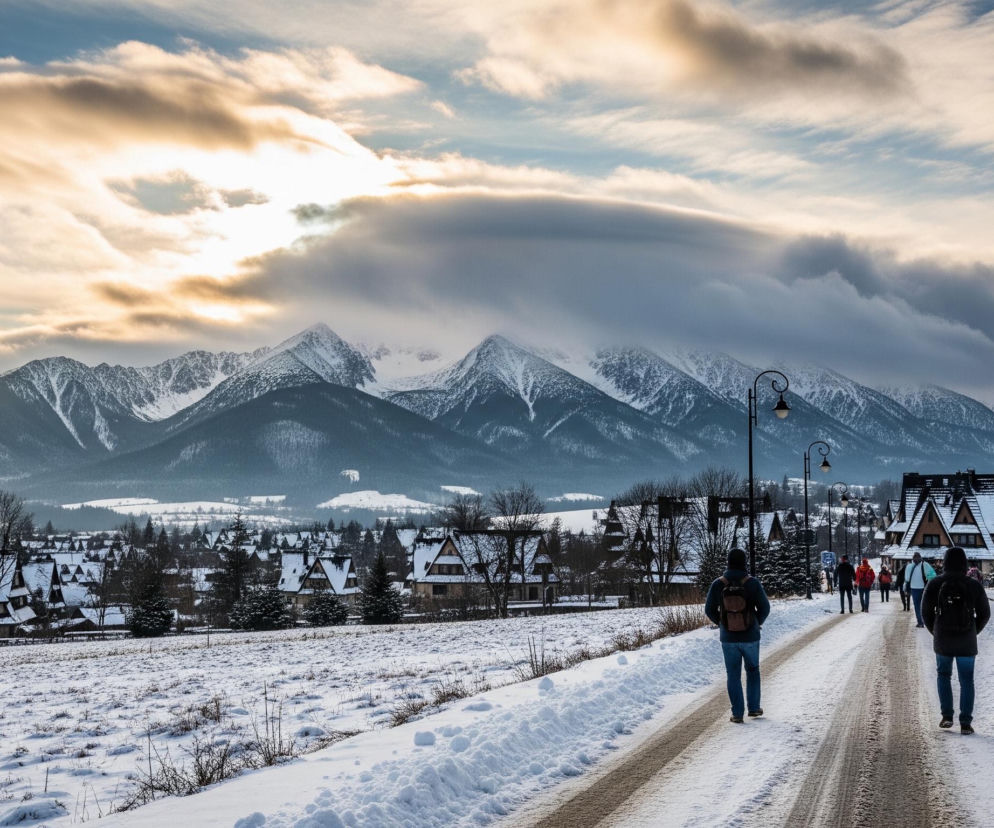 Głównym elementem są pokryte śniegiem góry, zajmujące tło obrazu, z jaśniejącym niebem w górnej części, gdzie złote i szare chmury rozświetla słońce. Na pierwszym planie po prawej stronie idzie grupa ludzi w kurtkach, z plecakami, po zaśnieżonej drodze, która ma widoczne ślady opon w jej centralnej części. Po lewej stronie drogi rozciąga się zaśnieżone pole z wystającymi suchymi trawami, a dalej widać szereg domów z dwuspadowymi dachami, również pokrytymi grubą warstwą śniegu.