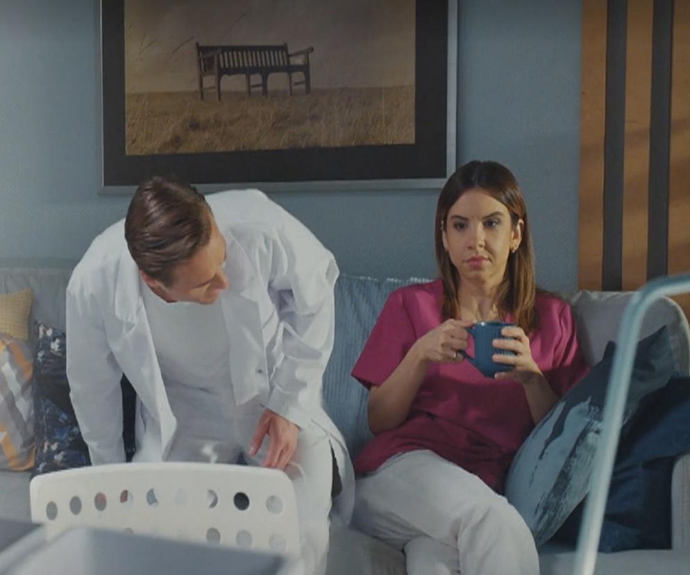 Aneta (Ilona Janyst) siedząca na kanapie z kubkiem w ręku, obok niej Olek (Maurycy Popiel) w białym kitlu, pochylający się. Para rozmawia o Kasi i Mariuszu. Zobacz więcej w Super Seriale.