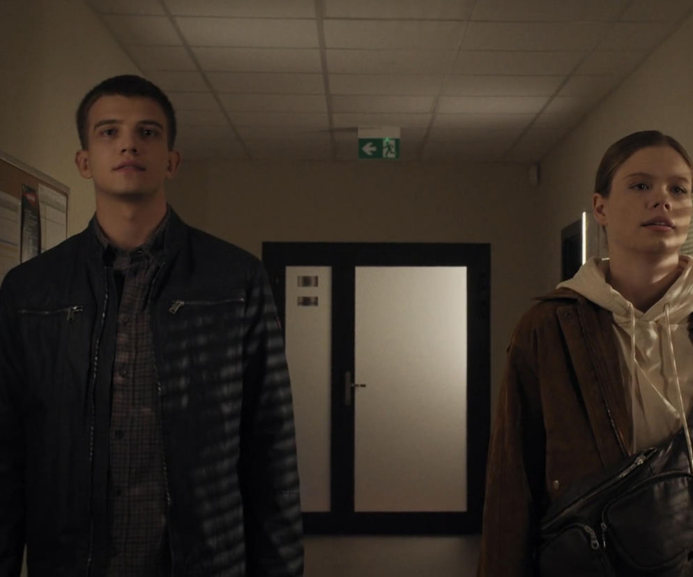 Mateusz (Rafał Kowalski) i Majka (Matylda Giegżno) z serialu M jak miłość stoją w korytarzu akademika. Mateusz, ubrany w ciemną kurtkę, patrzy prosto, a Majka w brązowej kurtce i beżowej bluzie z kapturem, z czarną nerką przewieszoną przez ramię, patrzy w prawo. To kluczowa scena z nadchodzącego odcinka, gdzie dowiadują się o śmierci ojca Tomka. Więcej o Super Serialach znajdziesz na naszym portalu.