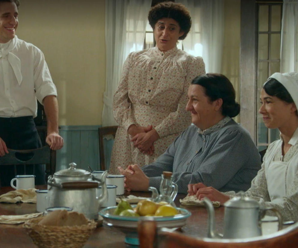 Cztery postacie z serialu La Promesa, w tym Simona i Candela, siedzą lub stoją wokół stołu, na którym znajdują się filiżanki i dzbanki. Postać Jany Expósito (Ana Garcés) jest również widoczna. Dowiedz się więcej o ich losach w Super Seriale.