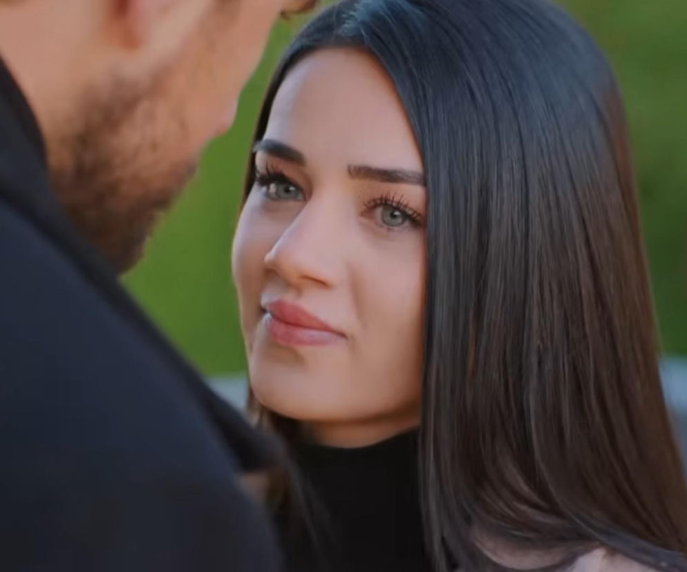 Bahar z serialu Miłość i nadzieja w zbliżeniu na twarz, z długimi, ciemnymi włosami, patrzy w kierunku Kuzeya, którego widać fragment ramienia i boku głowy, na zielonym tle. Więcej o ich losach na Super Seriale.