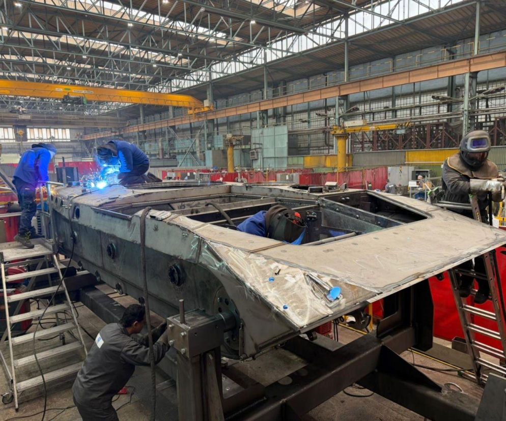 Spawacze pracujący przy kadłubie wozu BMP-1 w hali fabrycznej. O nowej produkcji zbrojeniowej przeczytasz na SE Portal Obronny.