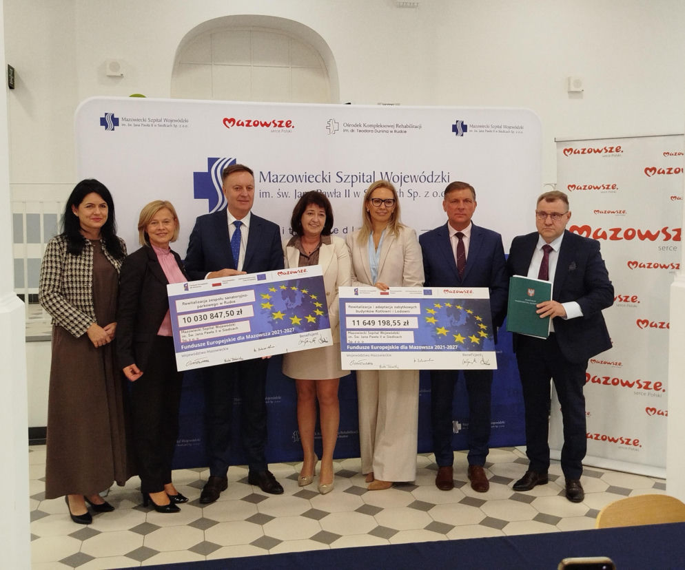 Siedem osób trzyma symboliczne czeki na rewitalizację w Rudce. O dotacji z UE przeczytasz na Eska Siedlce.