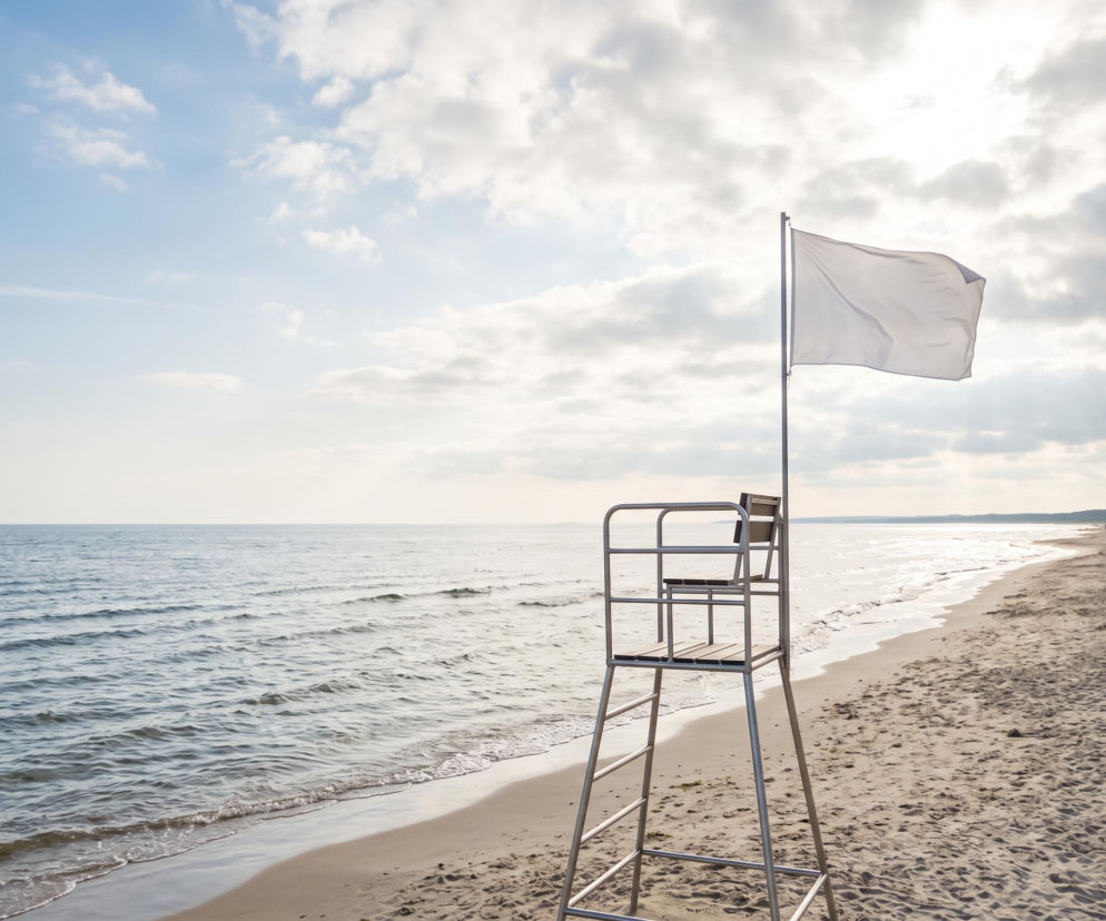 Biała flaga na wieży ratowniczej przy pustej plaży w Świnoujściu. O warunkach kąpieli przeczytasz na SE Szczecin.
