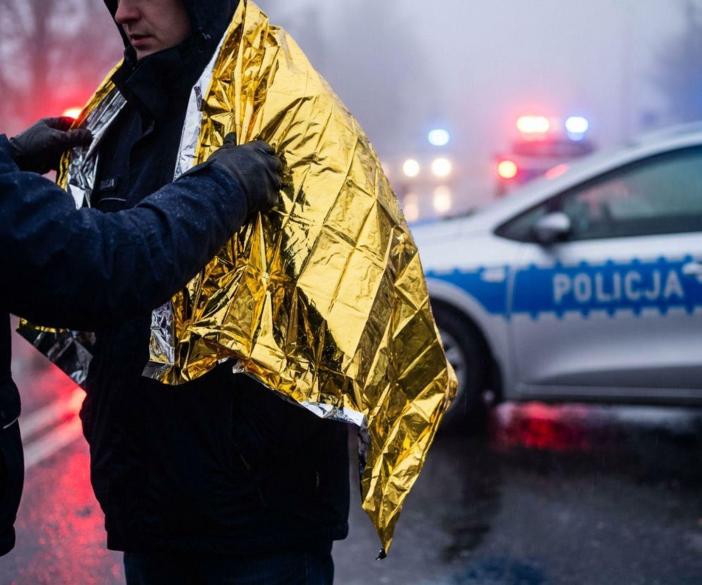 Policjant okrywający ocaloną osobę kocem termicznym