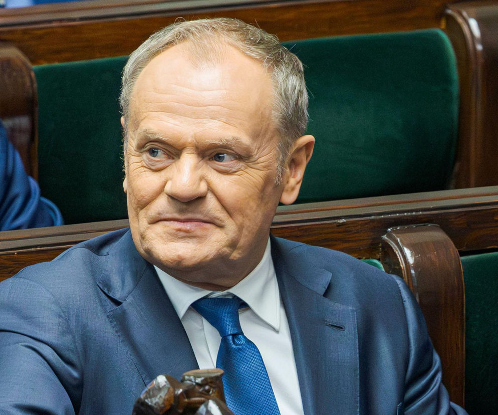 Premier Donald Tusk siedzi w sejmowej ławie i lekko się uśmiecha. O wynikach sondażu dla rządu przeczytasz na SE Polityka.
