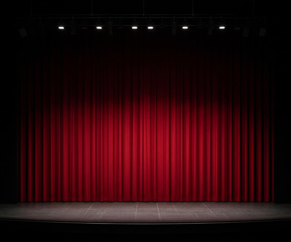 Przedstawiona jest scena teatralna z zamkniętą, marszczoną, intensywnie czerwoną kurtyną, która dominuje centralną część obrazu. Przed kurtyną znajduje się ciemna podłoga sceny, subtelnie oświetlona, z widocznymi jasnymi liniami dzielącymi ją na równe kwadraty. Górna część obrazu ukazuje rząd sześciu reflektorów scenicznych, z których trzy po lewej i trzy po prawej stronie świecą intensywnym, białym światłem, skierowanym na kurtynę. Pozostałe obszary wokół sceny są pogrążone w głębokiej czerni, tworząc kontrast i podkreślając oświetlone elementy.