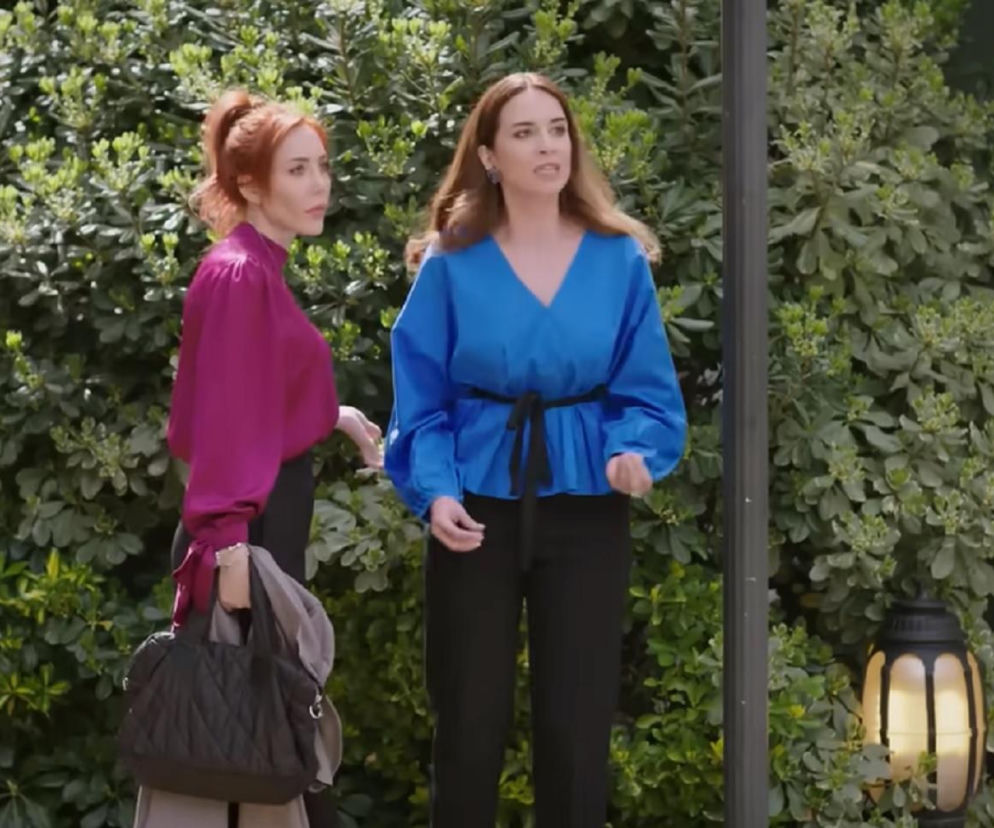 Aktorki Çisel Kuskan (Beyza) w niebieskiej bluzce i Elif Çapkin (Yonca) w fioletowej bluzce z czarną torbą, stojące przed zielonymi krzewami, dyskutujące o decyzji Yoncy o przerwaniu ciąży i ryzykownym planie Beyzy w serialu Panna młoda na Super Seriale.