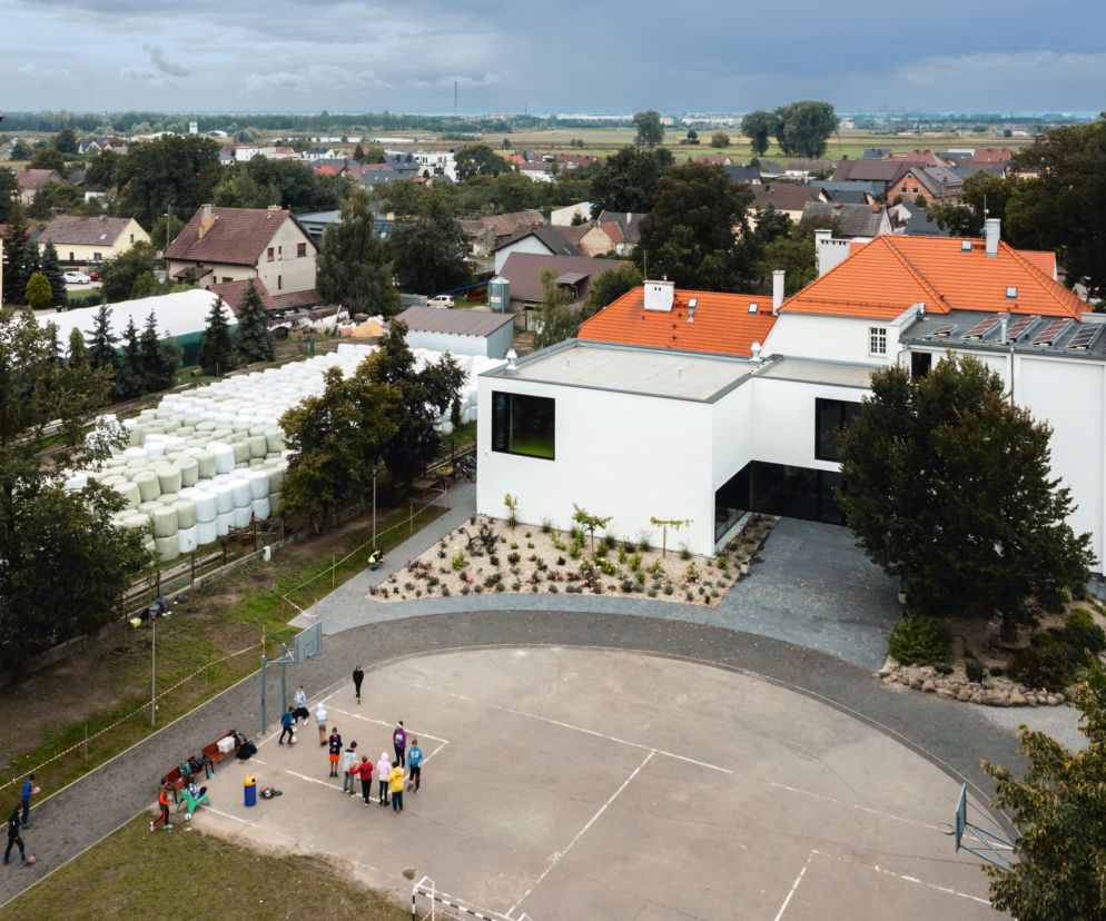 Nowoczesny budynek przedszkola Liberis w Silezji, zlokalizowany obok starszej zabudowy wiejskiej i kościoła. Architektura Murator Plus to miejsce, gdzie można czytać o projektach Marcin Kolanusa, łączących innowacyjność z poszanowaniem kontekstu miejsca, w tym termomodernizacji.