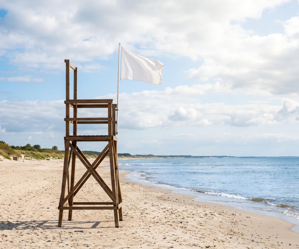 Drewniana wieżyczka ratownicza z białą flagą na plaży w Ustroniu Morskim. O bezpiecznej kąpieli przeczytasz na SE Szczecin.