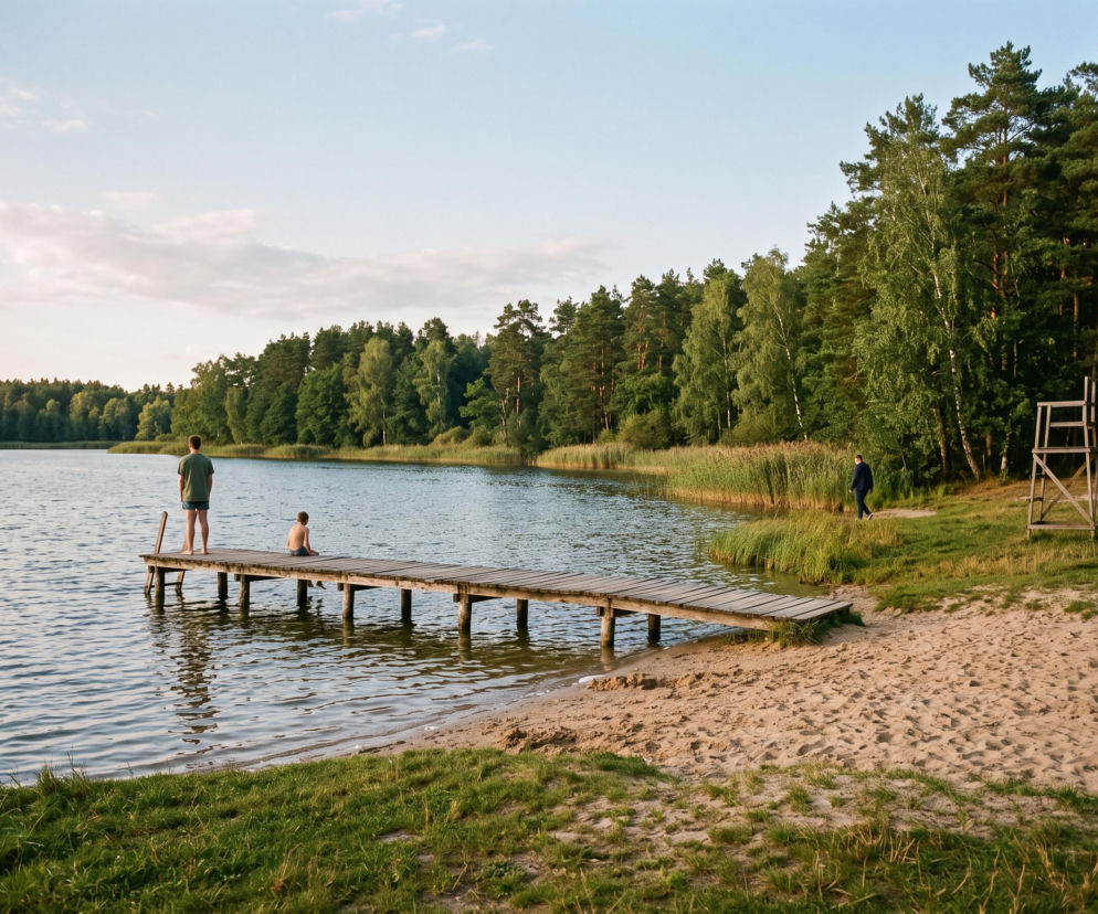 Dwie osoby na molo przy piaszczystej plaży nad zalewem. O miejscach na kąpiel blisko Biłgoraja dowiesz się z SE Lublin.