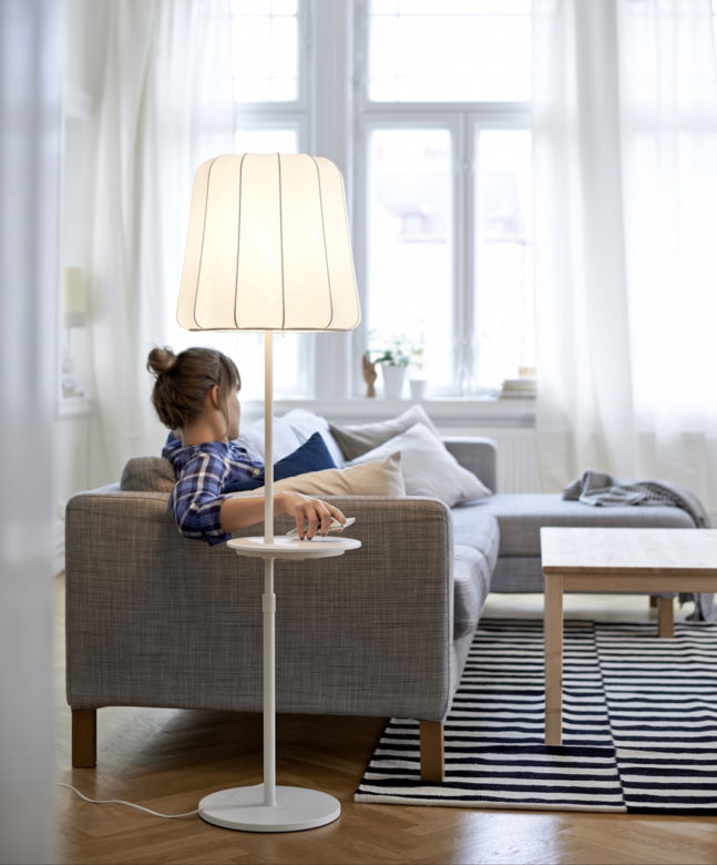 Lampa podłogowa z ładowarką ustawiona przy sofie