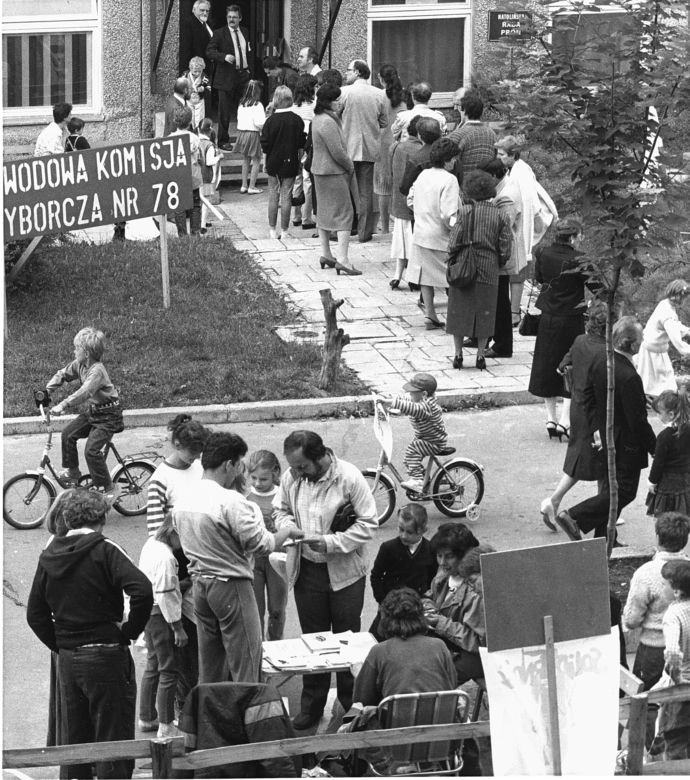 Kolejka głosujących oraz punkt informacyjny Solidarności przed lokalem wyborczym na Ursynowie, Warszawa, 4.06.1989. 